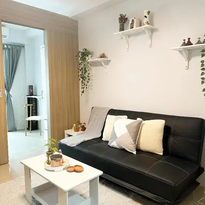 a living room with a black couch and a table at Crizzy's Hub Crizel at Shore Residences - 1BR with Balcony and Amenity view - Netflix and Disney - Near MOA in Manila