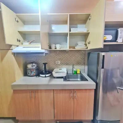 a small kitchen with a sink and a refrigerator at HOMELY Green 2 Residences near DLSUHSI in Dasmariñas