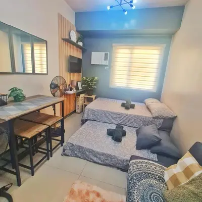 a room with three beds and a table and a dining room at HOMELY Green 2 Residences near DLSUHSI in Dasmariñas