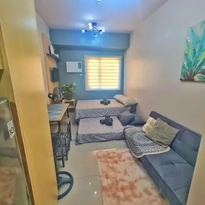 a living room with two beds and a blue couch at HOMELY Green 2 Residences near DLSUHSI in Dasmariñas