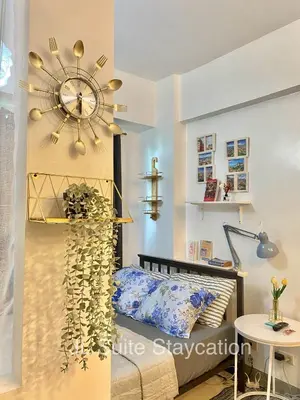 a bedroom with a bed and a clock on the wall at JL Suite Staycation near Venice Grand Canal Mall in Manila