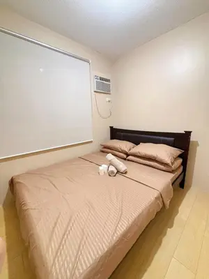 a bed with a teddy bear laying on it at Cozy 2BR Condo Free Pool Access in Manila