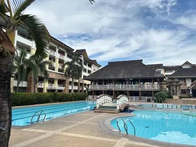 a resort with a swimming pool and a building at Cozy 2BR Condo Free Pool Access in Manila
