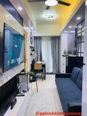 a living room with a blue couch and a large tv at Shore 3 - 1BR Scandi-Industrial Condo Suite by The Bay in Manila