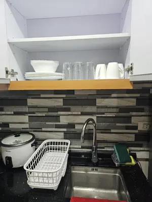 a kitchen counter with a sink and a shelf with dishes at Unit 14E Tower D, 1BR Unit- Manhattan Heights Cubao in Manila