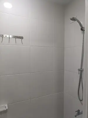 a white bathroom with a shower with a hose at Lyleis' Getaway in Manila
