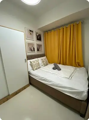 a bedroom with a bed with a yellow curtain at Happy Sunshine Staycation Moa near Airport in Manila