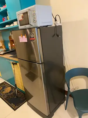 a refrigerator with a microwave on top of it at The Teal Deal in Manila