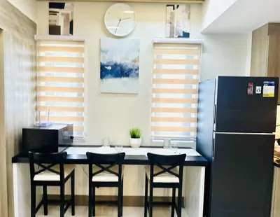a kitchen with a table with chairs and a refrigerator at Royal Fame Residency in Manila
