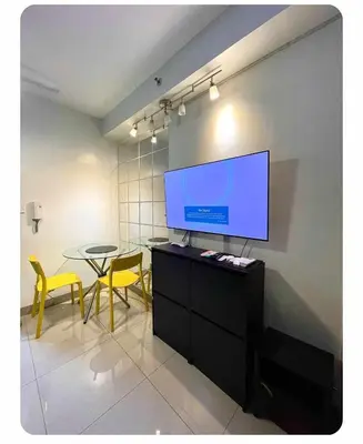 a living room with a tv and a table with yellow chairs at SHORE 2n3 RESIDENCES in Manila