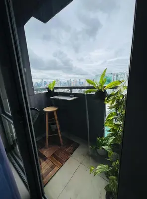 a balcony with a table and a stool and plants at Casa Tagpuan at Manhattan Heights in Manila