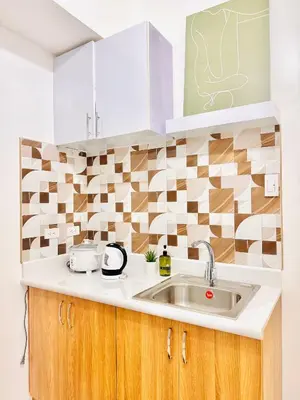 a kitchen with a sink and a tile wall at New Condo at Grand Riviera Suites across US Embassy in Manila