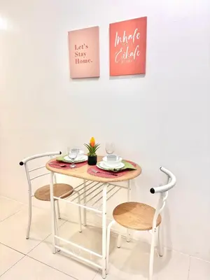 a table with two chairs and a table with two pictures on the wall at New Condo at Grand Riviera Suites across US Embassy in Manila
