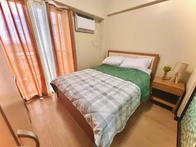 a small bedroom with a bed and a window at Calathea Luxe Atrium Suite in Manila