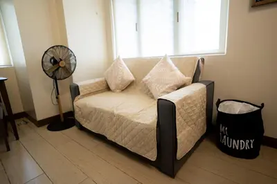 a living room with a couch and a fan at Elegant unit, fast wifi, near Makati Medical Centr in Manila