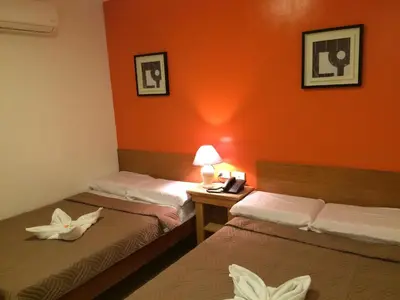 two beds in a room with orange walls at Stone House Hotel Pasay in Manila