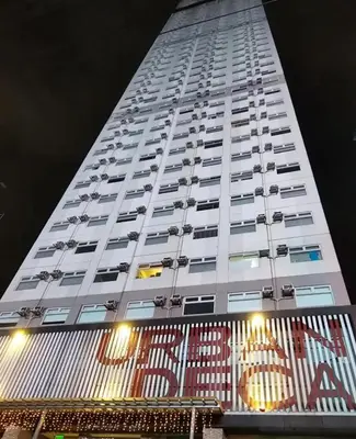 a tall white building with a sign in front of it at Jam Reid Condotel Mandaluyong in Manila