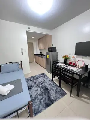 a room with a bed and a table and a kitchen at Unistay SHORE Residence amazing pool view in Manila