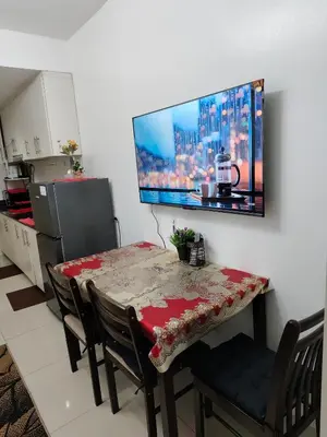 a dining room table with a television on the wall at Sea Residence MOA - JULIZA STAYCATION in Manila