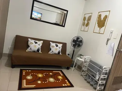 a living room with a couch and a mirror at 12 Minutes from Mall of Asia - Spacious Condo with Balcony & Hot Shower in Manila