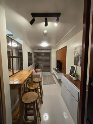 a kitchen with a bar with stools and a living room at Shore 3 Residences tower 3 in Manila