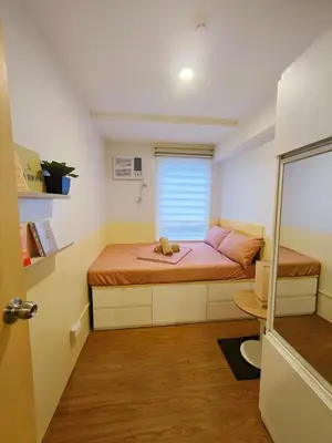 a small bedroom with a bed with pink sheets at 2BR Pasig Condo for Family or Group with Parking in Manila