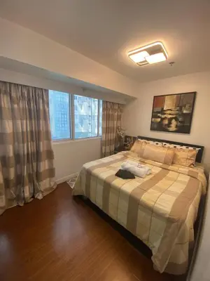 a bedroom with a bed and two large windows at ECN Suite and Staycation in Manila
