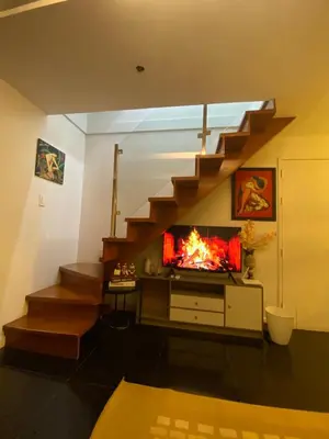 a living room with a fireplace under a staircase at ECN Suite and Staycation in Manila