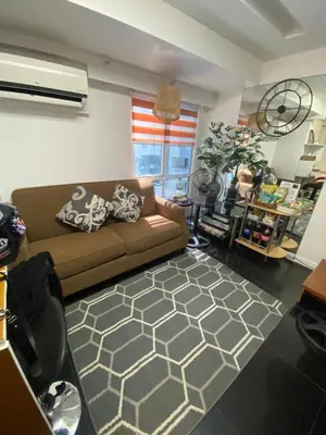 a living room with a brown couch and a rug at ECN Suite and Staycation in Manila