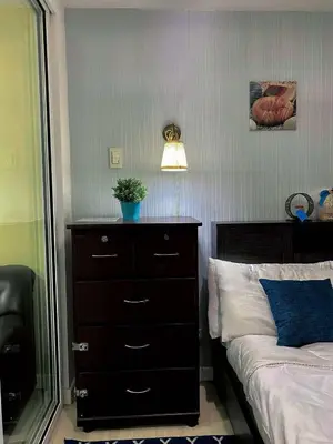 a bedroom with a dresser and a bed with a lamp at Yumi Azure Staycation in Manila