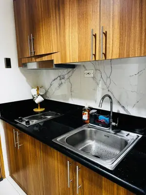 a kitchen with a stainless steel sink and wooden cabinets at A2 Condotel Suites in Manila
