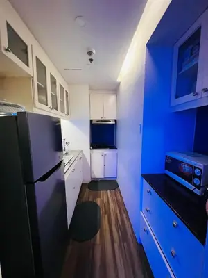 a kitchen with a black refrigerator and white cabinets at Pinecrest Residential Condominium Newport Pasay City in Manila