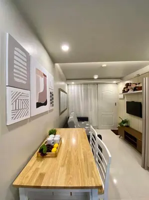 a dining room with a wooden table and chairs at Cozy Studio Sorrento Oasis Rosario Pasig in Manila