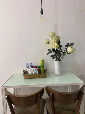 a table with a vase of flowers and two chairs at Ohana buenbyahe affordable staycation at F RESIDENCEs near at mrt shaw megamall and starmall in Manila