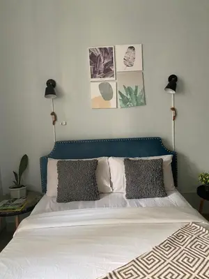 a bedroom with a bed with a blue headboard and two lamps at Ohana buenbyahe affordable staycation at F RESIDENCEs near at mrt shaw megamall and starmall in Manila