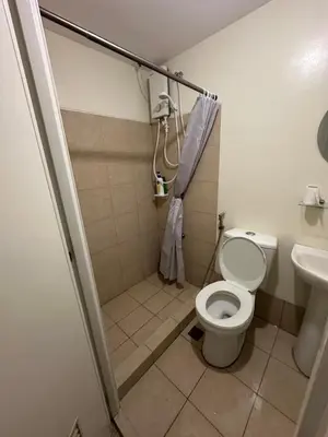 a small bathroom with a toilet and a shower at Stanford Suites 1 in Silang