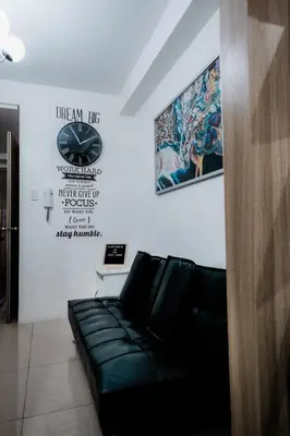 a living room with a black couch and a wall at Staycation near Moa new room in Manila