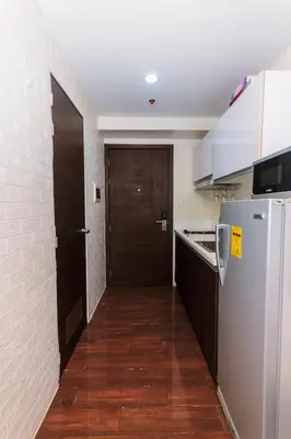 a hallway leading to a kitchen with a refrigerator at Eccentric Escape Stylish Makati Urban Swim Gym 4034 in Manila
