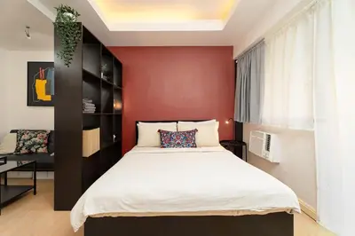 a bedroom with a bed and a red wall at Tranquil Greenbelt Makati Condo - Free Pool Access in Manila
