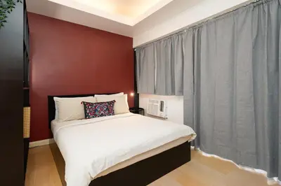 a bedroom with a white bed and a red wall at Tranquil Greenbelt Makati Condo - Free Pool Access in Manila