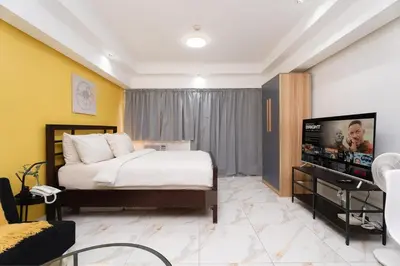 a bedroom with a bed and a flat screen tv at Greenbelt Makati Condo with Balcony & Park Views in Manila