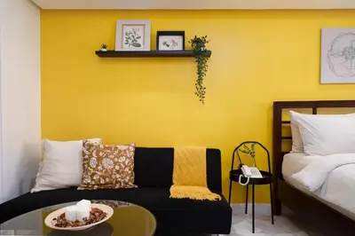 a living room with a couch and a yellow wall at Greenbelt Makati Condo with Balcony & Park Views in Manila