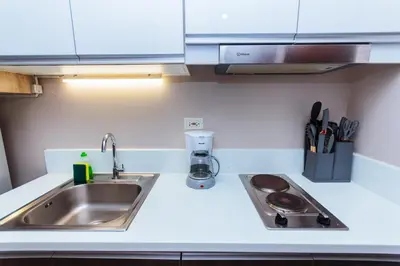 a kitchen counter with a sink and a stove at The Laughing Loft Cosmopolitan Comfort Gym Swim Park 2428 in Manila