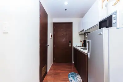 a small kitchen with a refrigerator and a door at Serene City Stay Trendy Cozy Makati Condo Fun Swim Gym Netflix 4047 in Manila