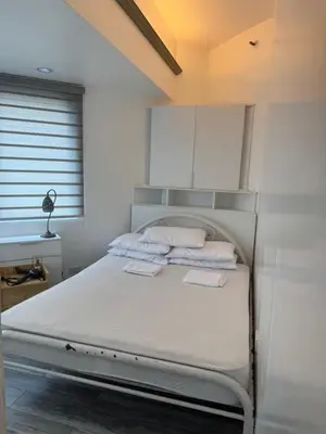 a bedroom with a white bed with white cabinets at Greenhills shopping center 2BR condominium in Manila