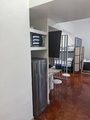 a kitchen with a refrigerator and a table with stools at Greenhills shopping center studio condominium in Manila