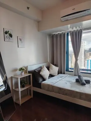 a bedroom with a bed and a large window at Cozy & Stylish Staycation and Netflix - WiFi and Pool in Manila