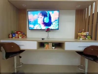 a desk with a television on a wall with two chairs at Shore residence Tower D moa ecom view cozy bedroom in Manila