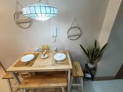 a dining room table with chairs and a potted plant at CLMN Staycation Metro Manila in Manila