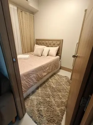 a small bedroom with a bed with white pillows at CLMN Staycation Metro Manila in Manila